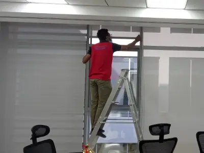 A woman manually pulling down a Sunscreen Roller Blind